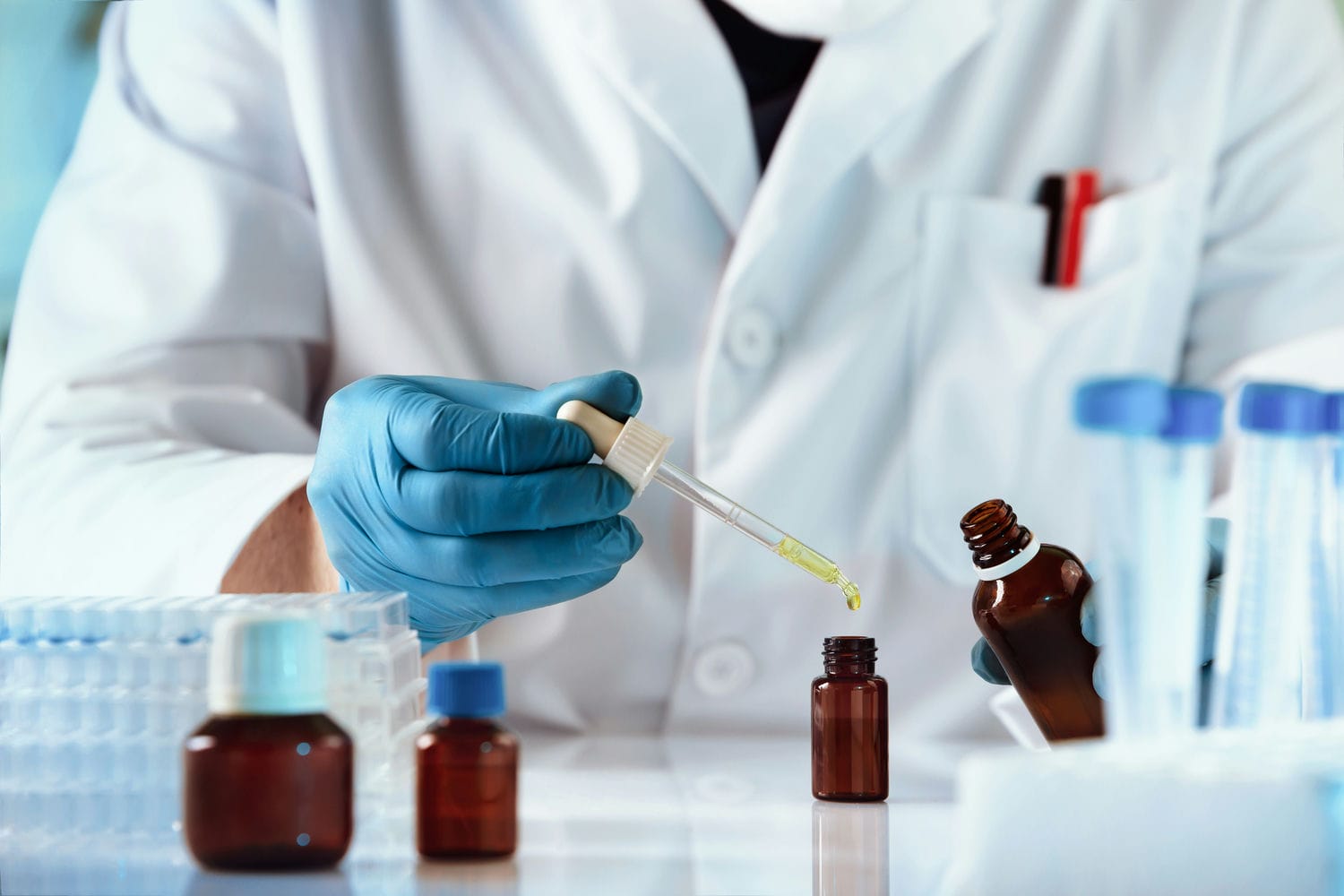 Compounding pharmacist using a dropper to fill an amber bottle with a custom formulation