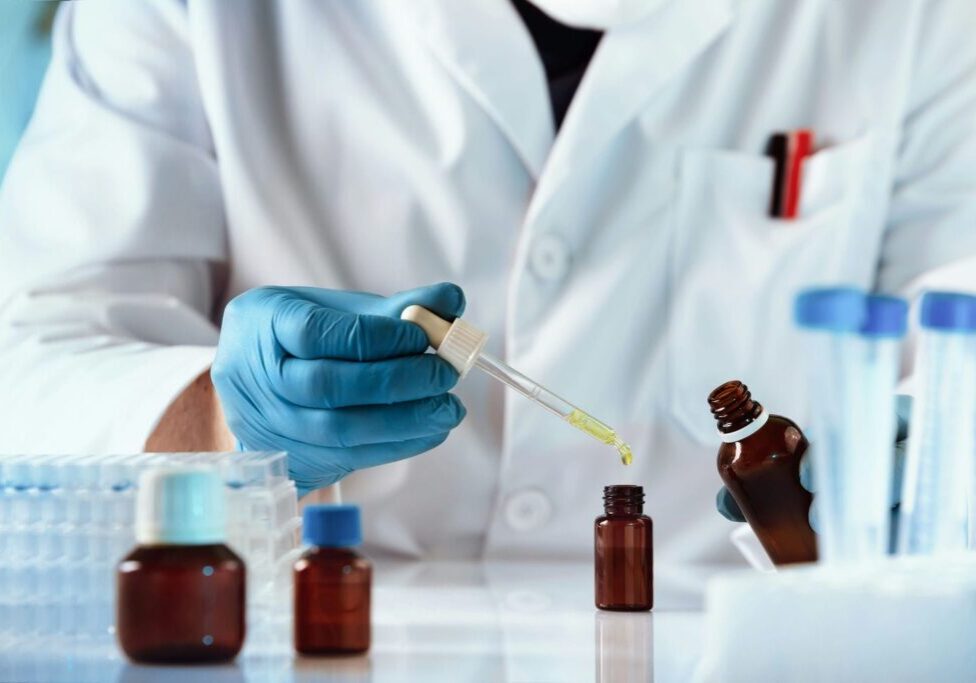 Compounding pharmacist using a dropper to fill an amber bottle with a custom formulation